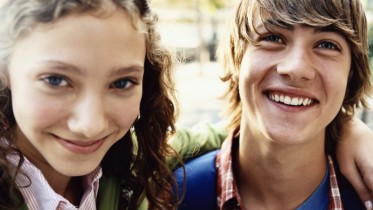 Teenage Girl Stands Smiling With Her Arm Around Her Friend