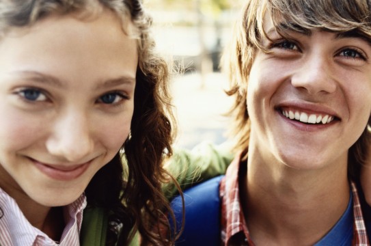 Teenage Girl Stands Smiling With Her Arm Around Her Friend